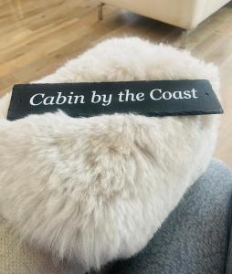 un libro sobre un cojín de piel blanca con las palabras cabina de la costa en Cabin by the coast, en Edimburgo
