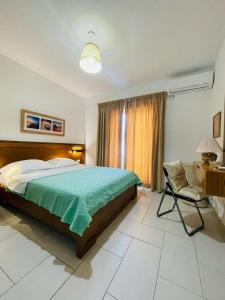 1 dormitorio con 1 cama, 1 silla y 1 ventana en Menikos Apartments, en Himare