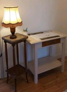 a table with a lamp and a desk with a book on it at Villa B in La neuville roy