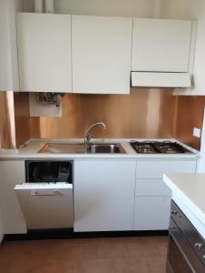 una cocina con armarios blancos y fregadero en Appartamento Velvet Beach, en Senigallia