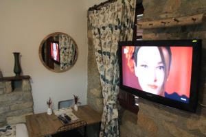 a television in a room with a stone wall at Eski Datça Pansiyon in Datca
