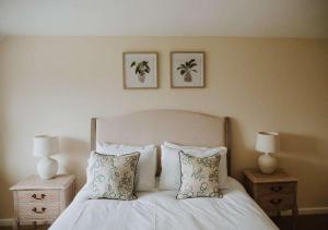 a bedroom with a white bed with two nightstands and two lamps at Aynho Cottages in Banbury