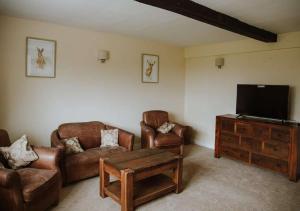 sala de estar con muebles de cuero y TV de pantalla plana en Aynho Cottages, en Banbury