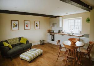 a living room with a couch and a table and a kitchen at Aynho Cottages in Banbury