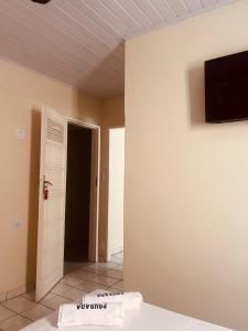 um quarto com uma porta e uma televisão na parede em Pousada Castanheira em Guarapari