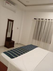 Cama blanca en habitación con espejo y ventana en Villa de luxe avec piscine, en Jaffna