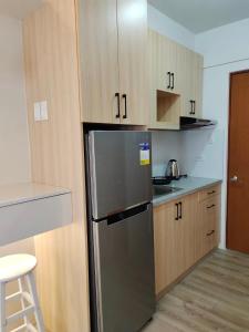 a kitchen with a stainless steel refrigerator and wooden cabinets at Studio Type BNB Accommodation in Bacolod