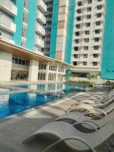 a row of lounge chairs next to a swimming pool in a building at Studio Type BNB Accommodation in Bacolod
