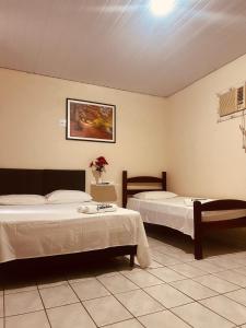 um quarto com duas camas e uma foto na parede em Pousada Castanheira em Guarapari