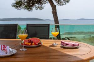 een tafel met twee glazen sinaasappelsap en een schaal fruit bij Villa Serenum in Šibenik