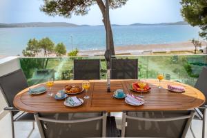 un tavolo in legno con bicchieri da cibo e vino sul balcone di Villa Serenum a Šibenik