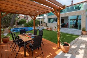 a patio with a table and chairs under a wooden pergola at Villa Serenum in Šibenik