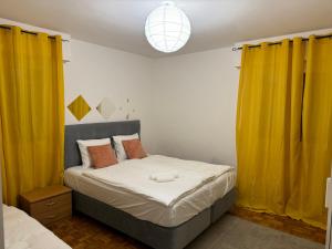 1 dormitorio con 1 cama con cortinas amarillas en Apartahotel Confort en Lausana