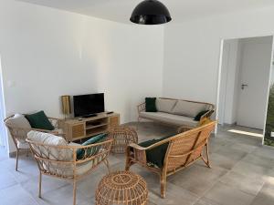 uma sala de estar com cadeiras de vime e um sofá em Maison neuve 4 etoiles à 10 minutes de Royan 