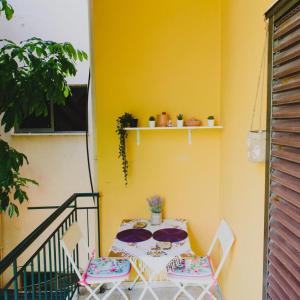 a table and chairs on a balcony with a yellow wall at Relaxation apartment in Messini