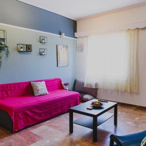 a living room with a pink couch and a table at Relaxation apartment in Messini