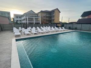 Una piscina con tumbonas blancas y un charco de agua. en Villa Raul, en Costinesti