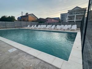 uma piscina com cadeiras brancas e uma cerca em Villa Raul em Costinesti