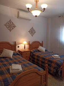 1 dormitorio con 2 camas y lámpara de araña en Quevoy, en Alcañiz