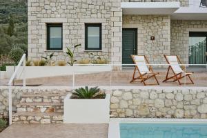 two chairs and a table in front of a house at Hermes Residence in Parga