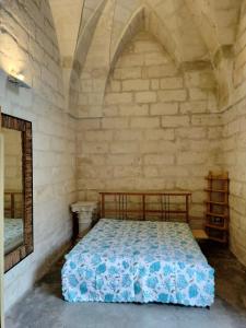 1 dormitorio con 1 cama en una pared de piedra en Camere Marta, en Minervino di Lecce