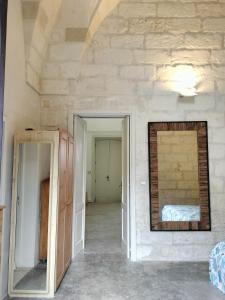 Habitación con pared de piedra y espejo. en Camere Marta, en Minervino di Lecce