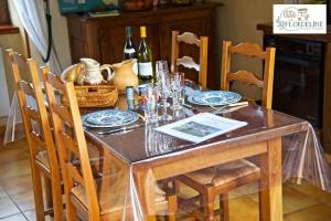 a dining room table with chairs and a table with wine bottles at LA FLORDELINE classé 2 étoiles draps et serviettes non fournis in Montbazens