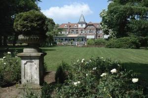 een park met een groot gebouw met een standbeeld in het midden bij Kasteel Wurfeld in Maaseik