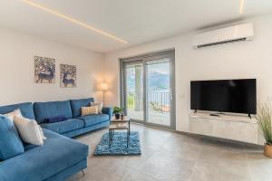a living room with a blue couch and a flat screen tv at VILLA SANT'ANNA - ALBA by Curtiaffitti in Pianello Del Lario