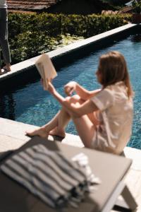 a woman sitting next to a pool reading a book at VILLA SANT'ANNA - ALBA by Curtiaffitti in Pianello Del Lario