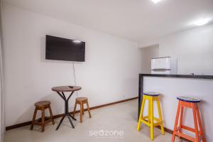 a room with three stools and a flat screen tv at CPR - Apartamentos a 200m da praia com Piscina in Marau