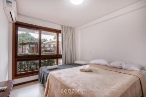 a bedroom with a bed and a large window at CPR - Apartamentos a 200m da praia com Piscina in Marau