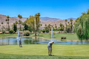 duas pessoas a jogar golfe em frente a um lago em Sunshine On My Shoulders Permit# STR2022-0160 em Palm Desert