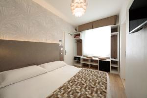 1 dormitorio con 1 cama blanca grande y ventana grande en Hotel Derby S, en Lido di Jesolo