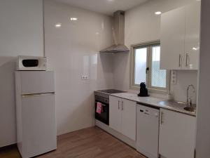 eine Küche mit weißen Schränken, einer Spüle und einem Kühlschrank in der Unterkunft Casa dúplex en el centro in Carmona
