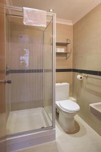 uma casa de banho com um WC e uma cabina de duche em vidro. em Linden House Hotel em Londres