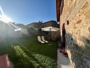 un jardin avec un parasol et des chaises ainsi qu'un bâtiment dans l'établissement Casa della Noce, à Vinci