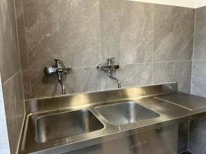 a stainless steel sink with two faucets on a wall at Campingplatz Mariengrund in Bernau am Chiemsee