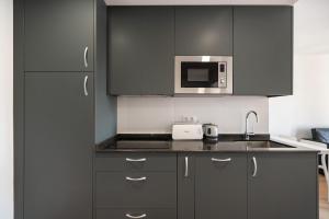 a kitchen with black cabinets and a sink and a microwave at dobohomes - Fernandez de los rios in Madrid