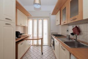 a kitchen with white cabinets and a sink and a table at C 'est la Vie in Lido di Ostia