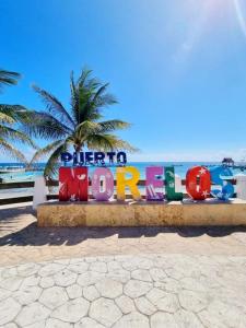 Home's Jungle Puerto Morelos Cancun 20 Minutes from the Airport في كانكون: علامة على الشاطئ مع نخلة في الخلفية