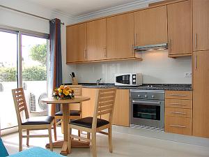a kitchen with wooden cabinets and a table with chairs at Apartamentos Turisticos Monte da Vinha II in Albufeira