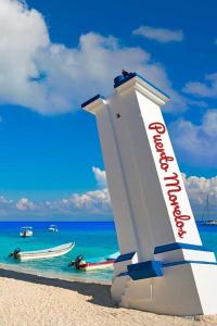坎昆的住宿－Home's Jungle Puerto Morelos Cancun 20 Minutes from the Airport，海滩上的标志,在水中划船