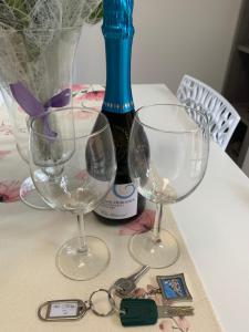 three wine glasses and a bottle on a table at Appartamenti Estera 2 in Malcesine
