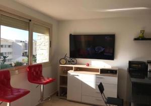 ein Wohnzimmer mit 2 roten Stühlen und einem Flachbild-TV in der Unterkunft Appart Residence Haut Standing in Bouznika