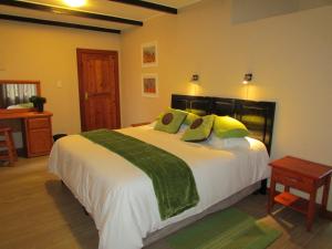 a bedroom with a large white bed with green pillows at Cottage Suikerbekkie in Dullstroom