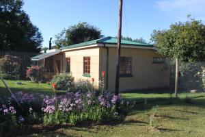 a small house with flowers in the yard at Cottage Suikerbekkie in Dullstroom