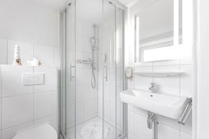 baño blanco con ducha y lavamanos en Auszeit Borkum, en Borkum