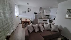 a living room with a couch with pillows and a kitchen at Apartman Petra s pogledom na more in Banjol