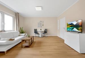 a living room with a white couch and a tv at Auszeit Borkum zentral & strandnah in Borkum